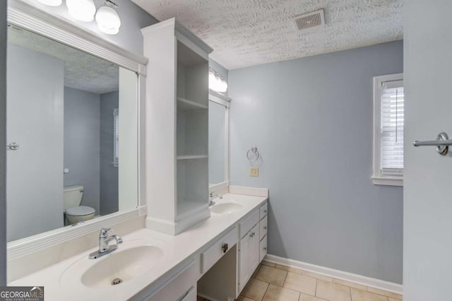 bathroom featuring visible vents, a sink, toilet, and double vanity