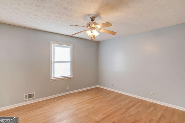 unfurnished room with light wood finished floors, baseboards, visible vents, ceiling fan, and a textured ceiling