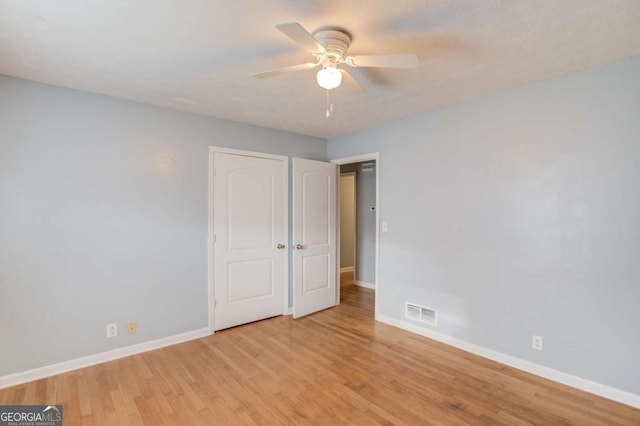 unfurnished bedroom with a ceiling fan, visible vents, baseboards, and wood finished floors