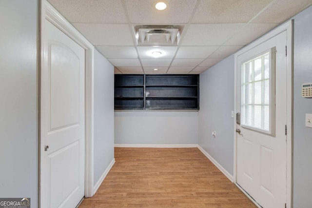 doorway featuring light wood finished floors, a paneled ceiling, visible vents, and baseboards