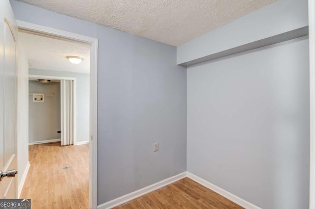 unfurnished room featuring light wood-style flooring, baseboards, and a textured ceiling