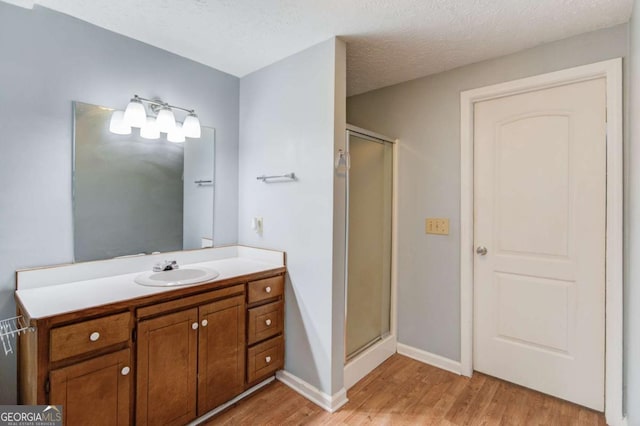 bathroom with a textured ceiling, a stall shower, and wood finished floors