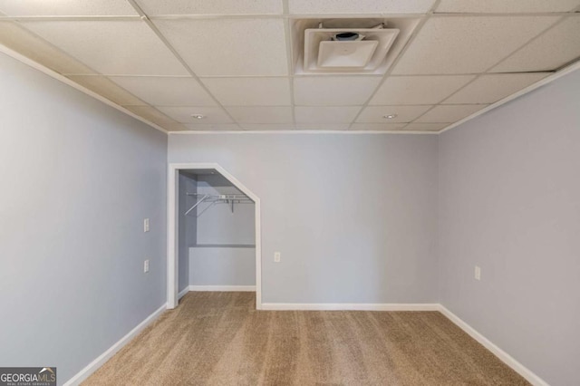 basement with carpet floors, a paneled ceiling, and baseboards