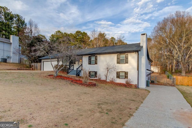 view of front of home with a garage, a chimney, and fence