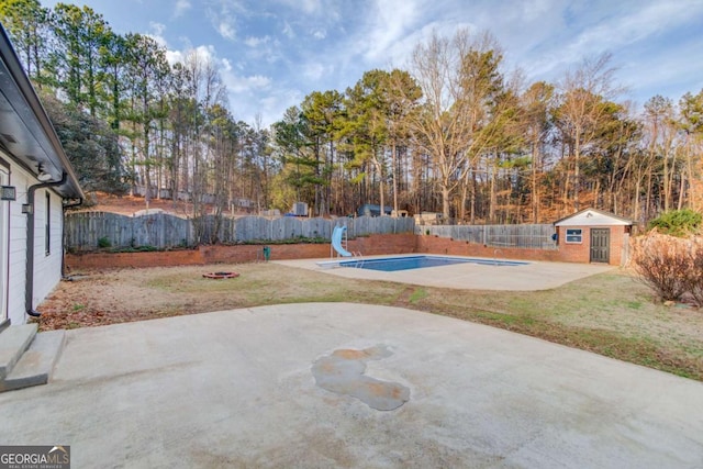 view of patio / terrace featuring an outdoor fire pit, a fenced backyard, a fenced in pool, and an outdoor structure