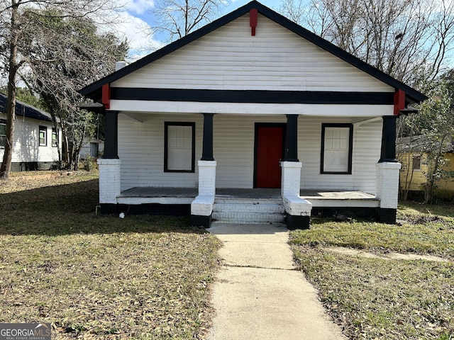 bungalow-style house featuring covered porch and a front lawn