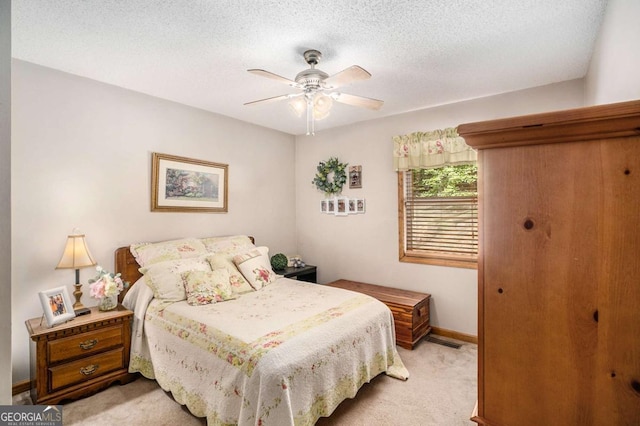 carpeted bedroom featuring ceiling fan and a textured ceiling