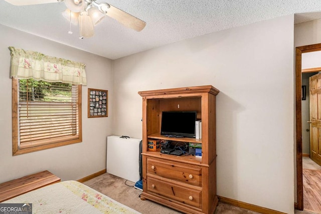 carpeted bedroom featuring ceiling fan and a textured ceiling