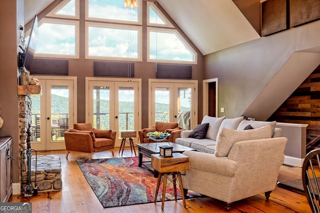 living room with high vaulted ceiling, french doors, and light wood-type flooring