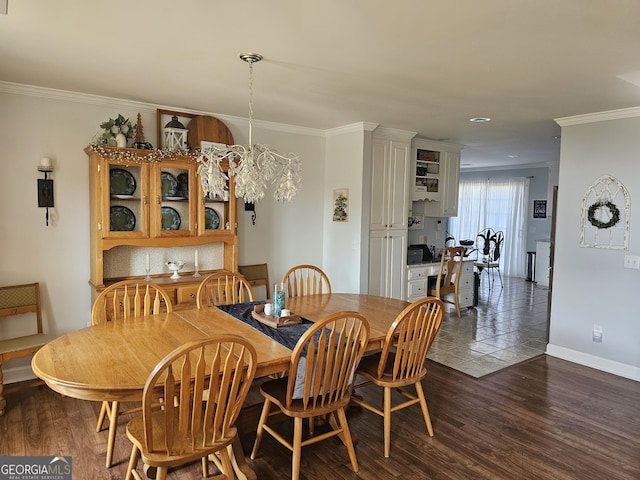 dining area with dark wood-type flooring, ornamental molding, and an inviting chandelier