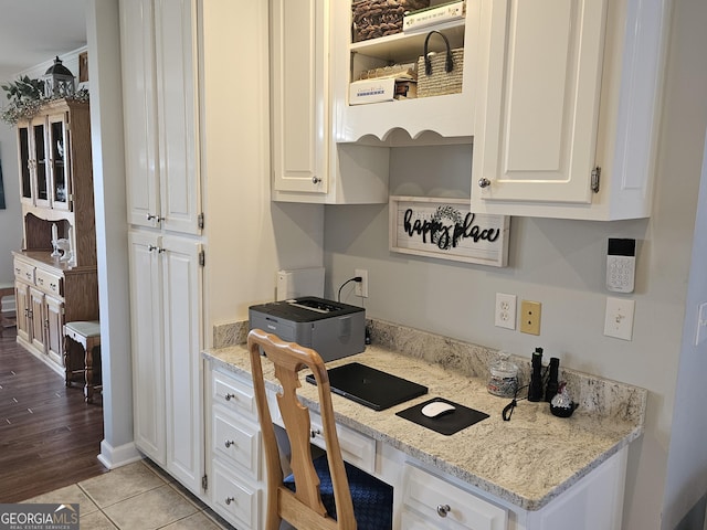 kitchen with white cabinetry, built in desk, and light stone countertops