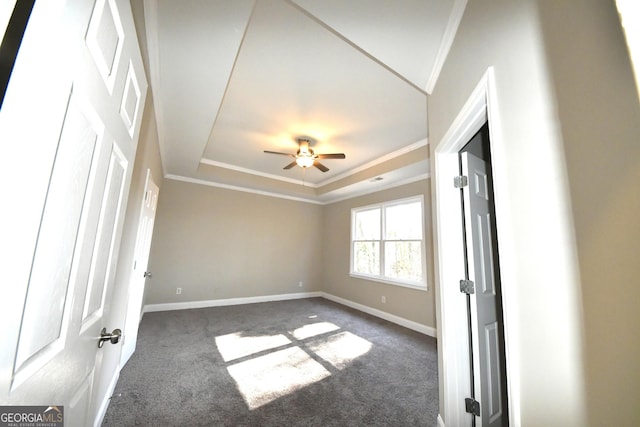 unfurnished room featuring ornamental molding, ceiling fan, dark carpet, and a tray ceiling