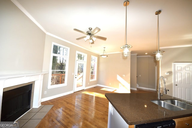 kitchen with sink, wood-type flooring, hanging light fixtures, ornamental molding, and black dishwasher