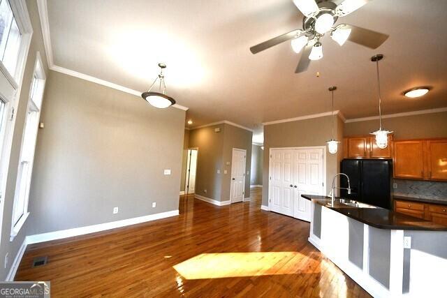 kitchen featuring black fridge, dark wood-type flooring, decorative backsplash, and pendant lighting