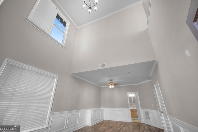 unfurnished living room with hardwood / wood-style flooring, ornamental molding, and ceiling fan with notable chandelier