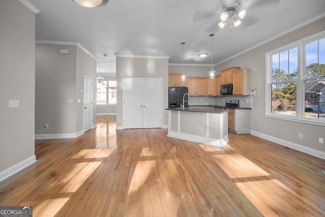 kitchen with light hardwood / wood-style flooring, backsplash, black appliances, a center island with sink, and decorative light fixtures