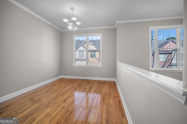 unfurnished room with hardwood / wood-style flooring, crown molding, and a notable chandelier