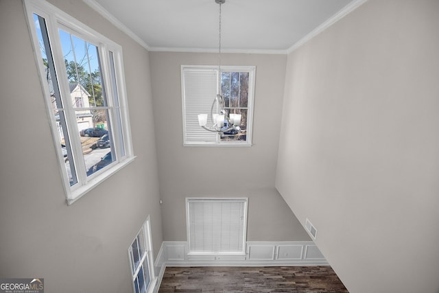 unfurnished dining area with dark hardwood / wood-style flooring, crown molding, and a chandelier