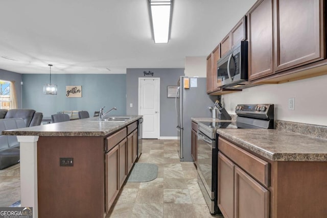 kitchen featuring appliances with stainless steel finishes, sink, a center island with sink, and decorative light fixtures