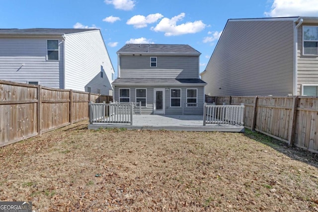 back of property featuring a wooden deck and a lawn