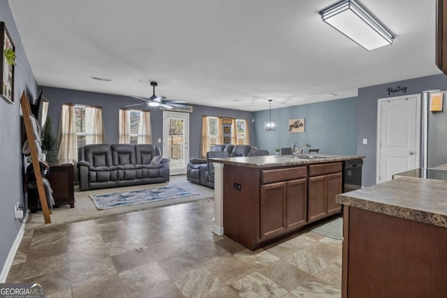 kitchen featuring hanging light fixtures, sink, ceiling fan, and a center island with sink