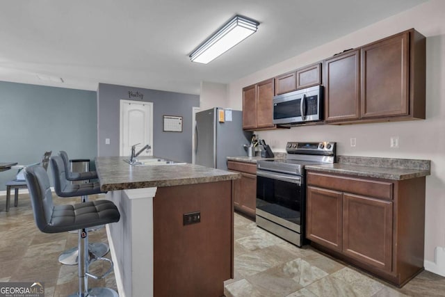 kitchen featuring stainless steel appliances, a kitchen bar, sink, and a center island with sink