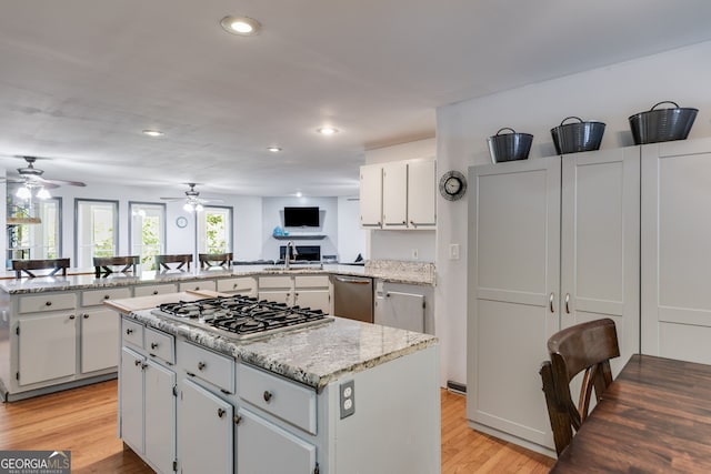 kitchen with white cabinetry, stainless steel appliances, a kitchen island, kitchen peninsula, and light wood-type flooring