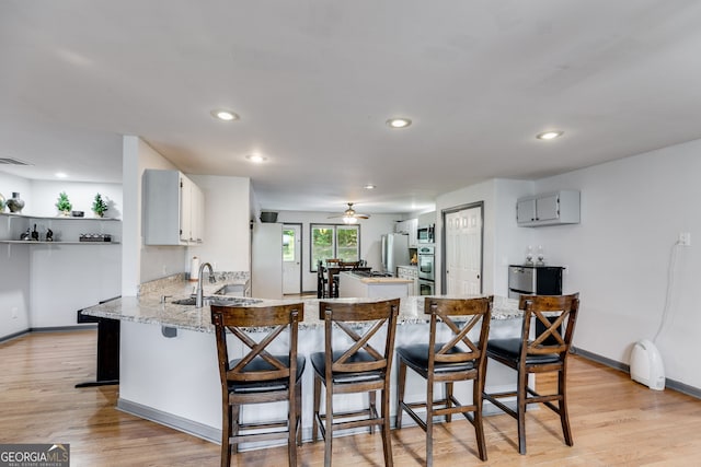 kitchen featuring sink, a breakfast bar area, light hardwood / wood-style flooring, appliances with stainless steel finishes, and kitchen peninsula