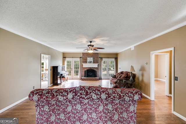 living room featuring hardwood / wood-style floors, crown molding, a fireplace, and french doors