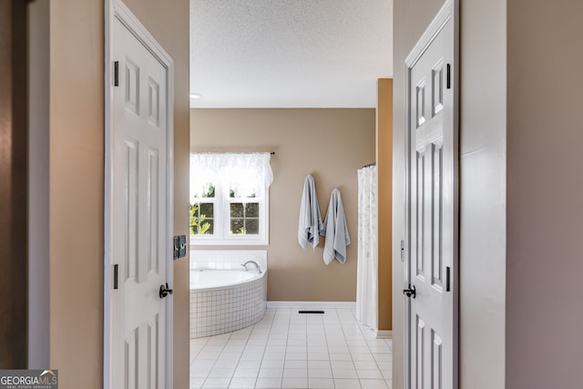 bathroom with tile patterned flooring, tiled tub, and a textured ceiling