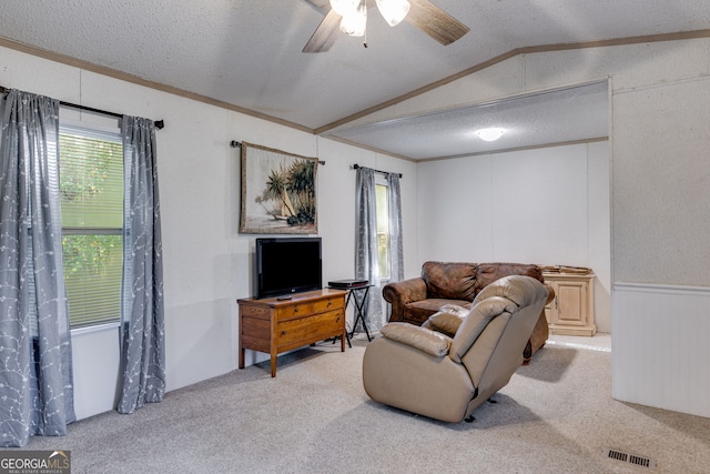 carpeted living room with crown molding, lofted ceiling, ceiling fan, and a textured ceiling