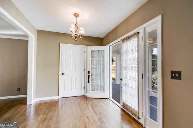 foyer entrance with a notable chandelier, light hardwood / wood-style floors, and a textured ceiling