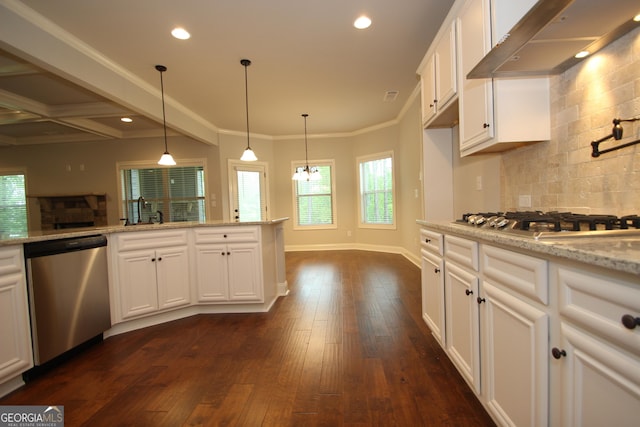 kitchen with appliances with stainless steel finishes, pendant lighting, white cabinetry, light stone countertops, and wall chimney exhaust hood