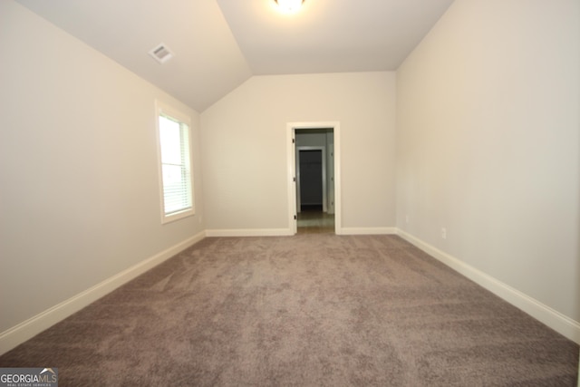 carpeted spare room featuring vaulted ceiling