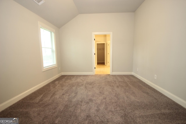 unfurnished bedroom with vaulted ceiling and carpet