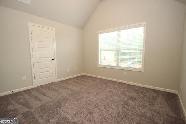 unfurnished room with lofted ceiling and dark carpet