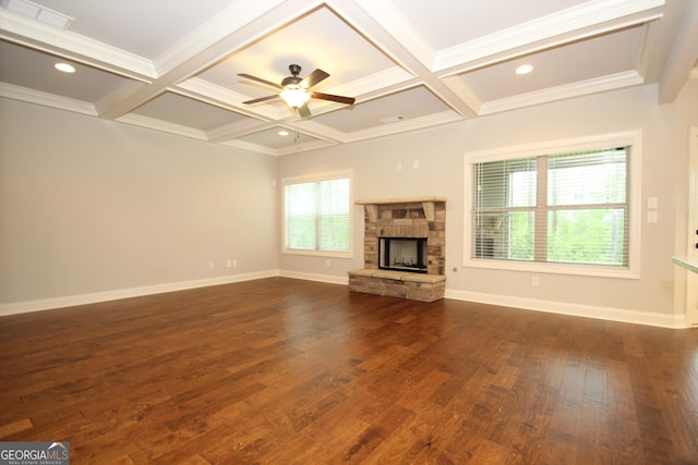 unfurnished living room with dark hardwood / wood-style floors, coffered ceiling, beam ceiling, and a stone fireplace