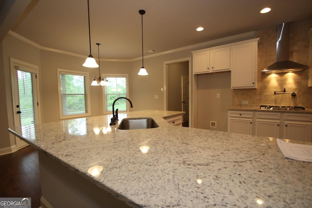 kitchen with wall chimney exhaust hood, light stone countertops, sink, and white cabinets