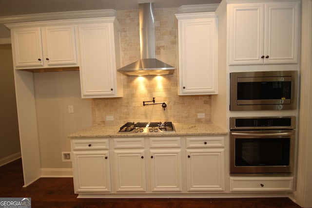 kitchen featuring white cabinetry, appliances with stainless steel finishes, and wall chimney range hood