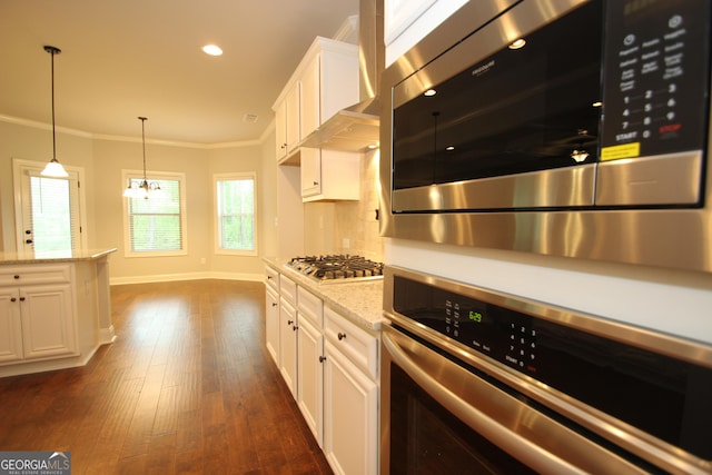 kitchen with light stone counters, crown molding, dark hardwood / wood-style flooring, stainless steel appliances, and white cabinets