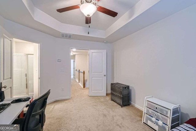 carpeted office featuring a raised ceiling and ceiling fan