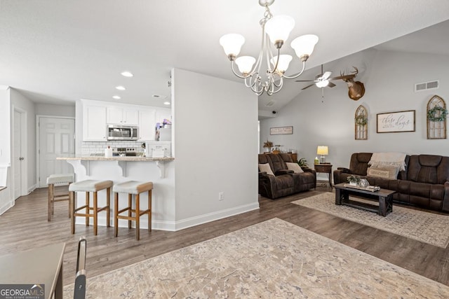 living room featuring lofted ceiling, dark hardwood / wood-style floors, and ceiling fan with notable chandelier