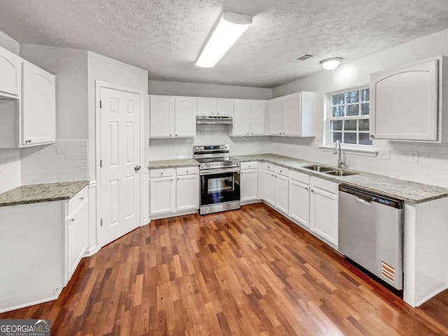 kitchen with sink, white cabinetry, light stone counters, appliances with stainless steel finishes, and dark hardwood / wood-style flooring