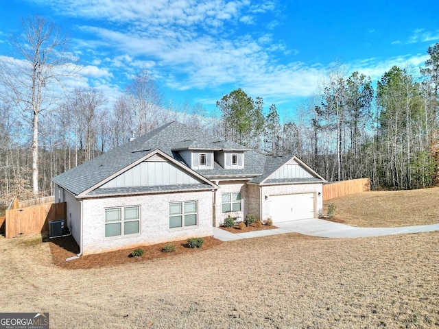 view of front of house with central AC, a garage, and a front lawn