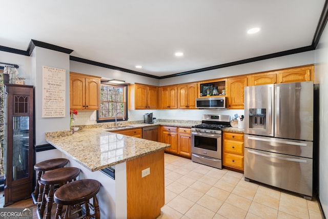 kitchen with kitchen peninsula, light stone countertops, sink, appliances with stainless steel finishes, and a kitchen bar