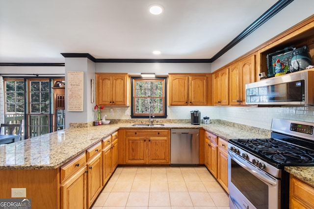 kitchen with appliances with stainless steel finishes, sink, kitchen peninsula, light stone countertops, and decorative backsplash