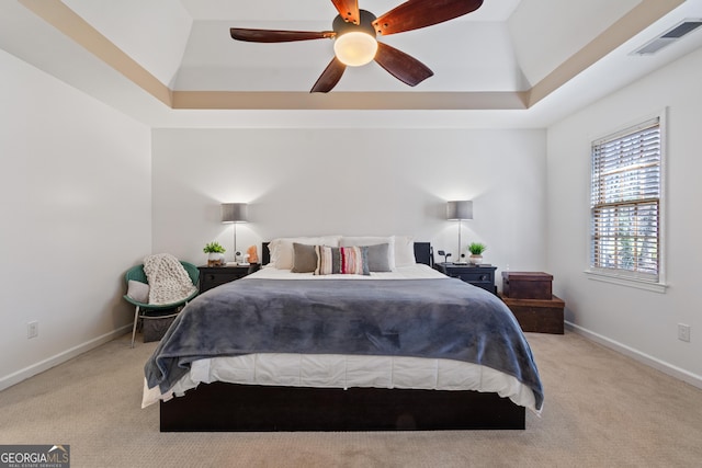 carpeted bedroom with a tray ceiling and ceiling fan