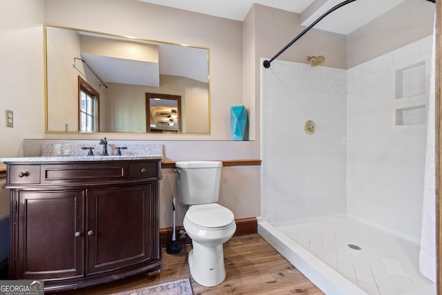 bathroom with tiled shower, wood-type flooring, vanity, and toilet