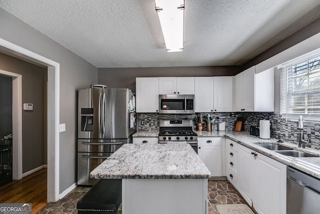 kitchen featuring appliances with stainless steel finishes, a kitchen island, sink, and white cabinetry