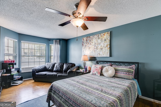 bedroom with hardwood / wood-style flooring, ceiling fan, and a textured ceiling